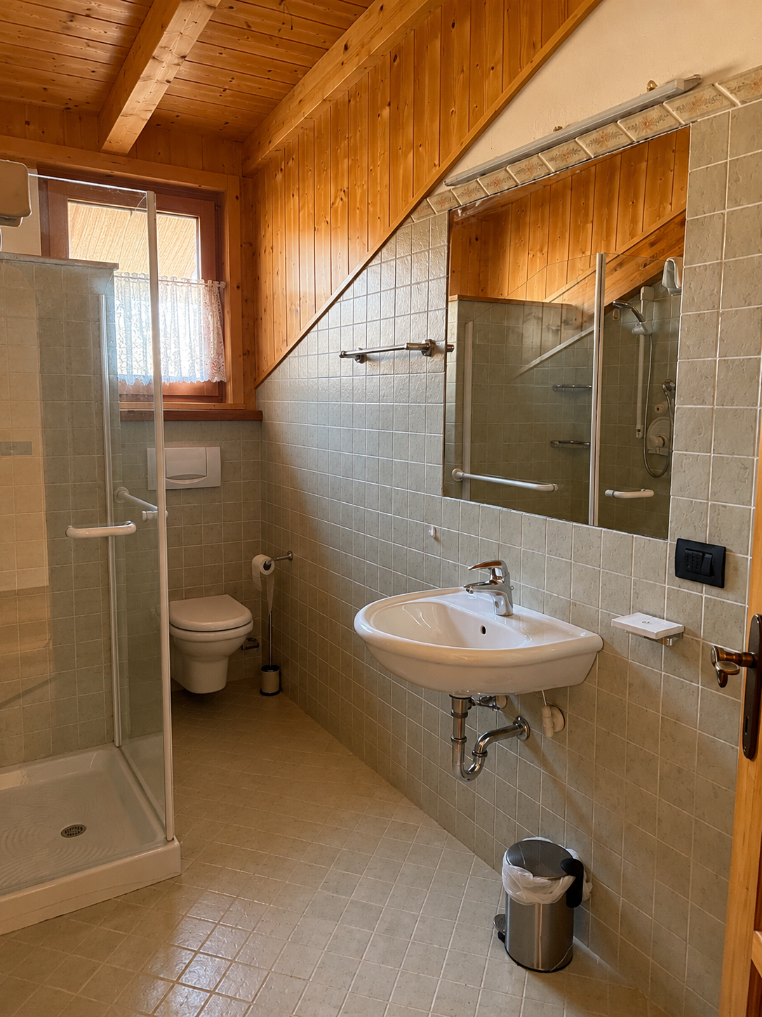Bagno mansardato con doccia Ciasa Le Giare - travi a vista, piastrelle beige, specchio ampio
