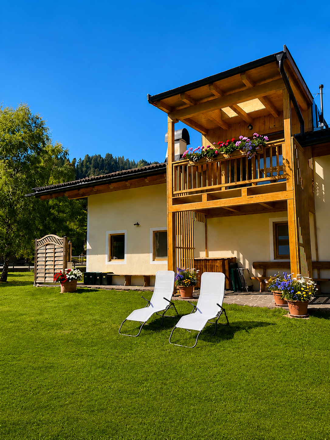Il giardino privato con sdraio e fiori: relax assoluto ai piedi delle Dolomiti